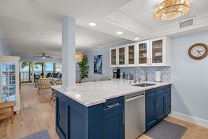 A kitchen with a large island, white cabinets, and a clock on the wall. - Surfside 123 Gorgeous and new to market! (Sanibel)