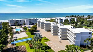 A hotel with multiple floors, a swimming pool, and a view of the beach.