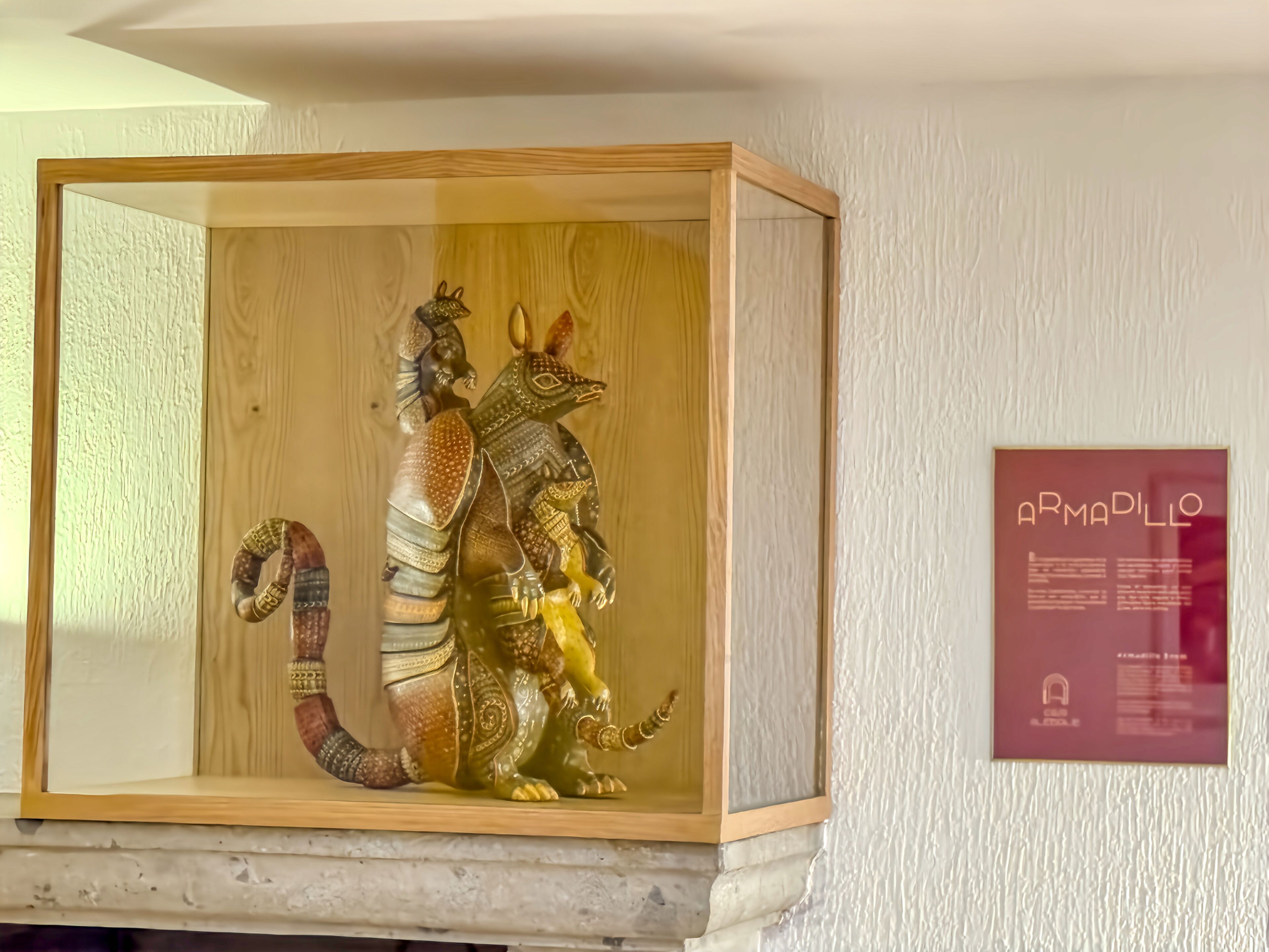 A display case containing a sculpture of a mythical creature with a long tail and a small dog-like figure.