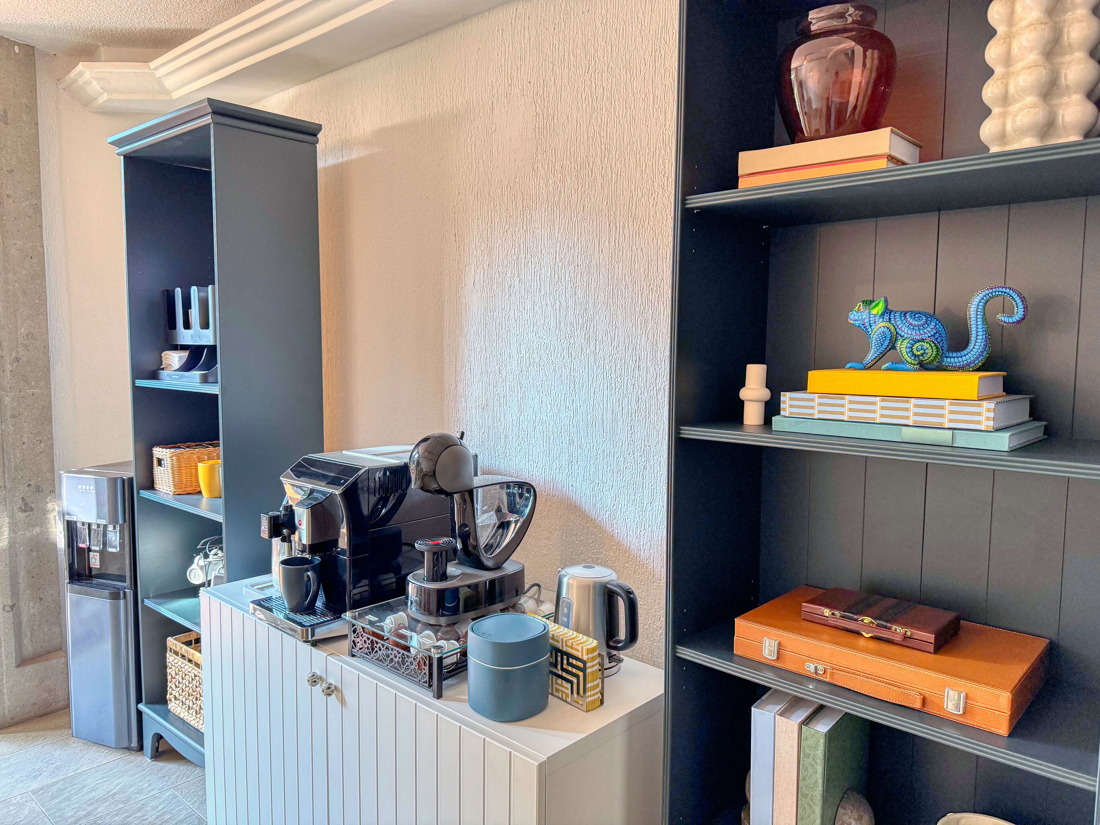 Ett modernt kök med en kaffemaskin, vattenkokare och diverse köksredskap på bänkskivan.