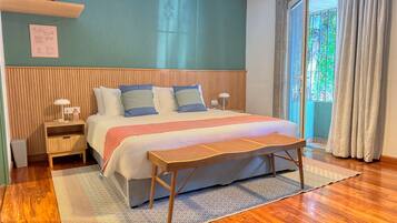 A neatly arranged bedroom with a bed, bedside tables, a nightstand, a bench, and a window with curtains.