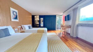 Habitación de hotel con dos camas, un escritorio, una silla, un espejo y vistas al exterior.
