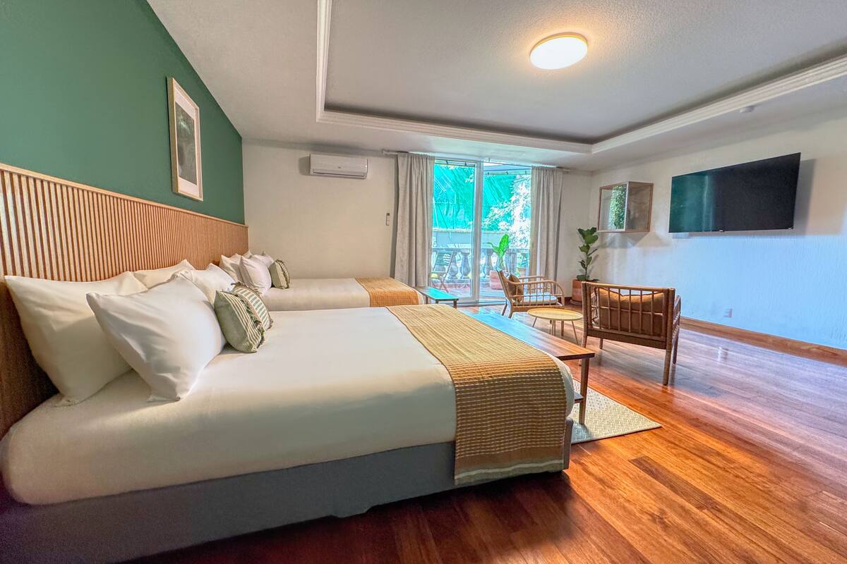 Une chambre d’hôtel avec un grand lit, un bureau et un téléviseur fixé au mur.