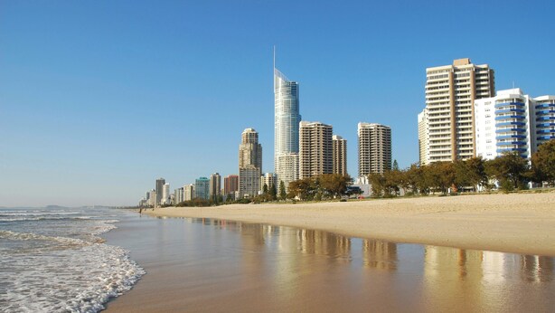 Stadsgezicht aan het strand met hoge gebouwen, een zandstrand en oceaan.