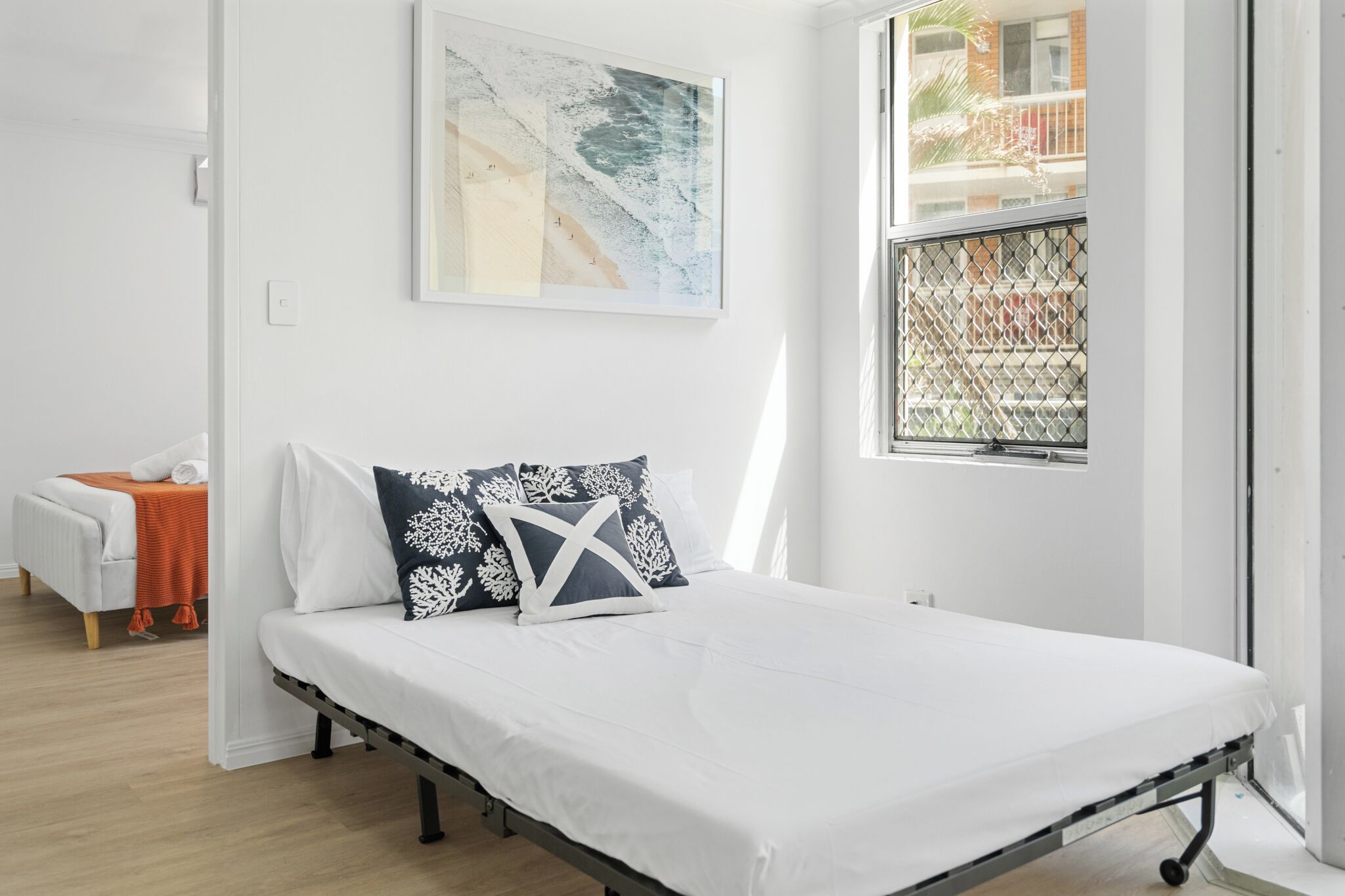 Une chambre à coucher moderne avec un lit, une fenêtre donnant sur un balcon et un tableau accroché au mur.