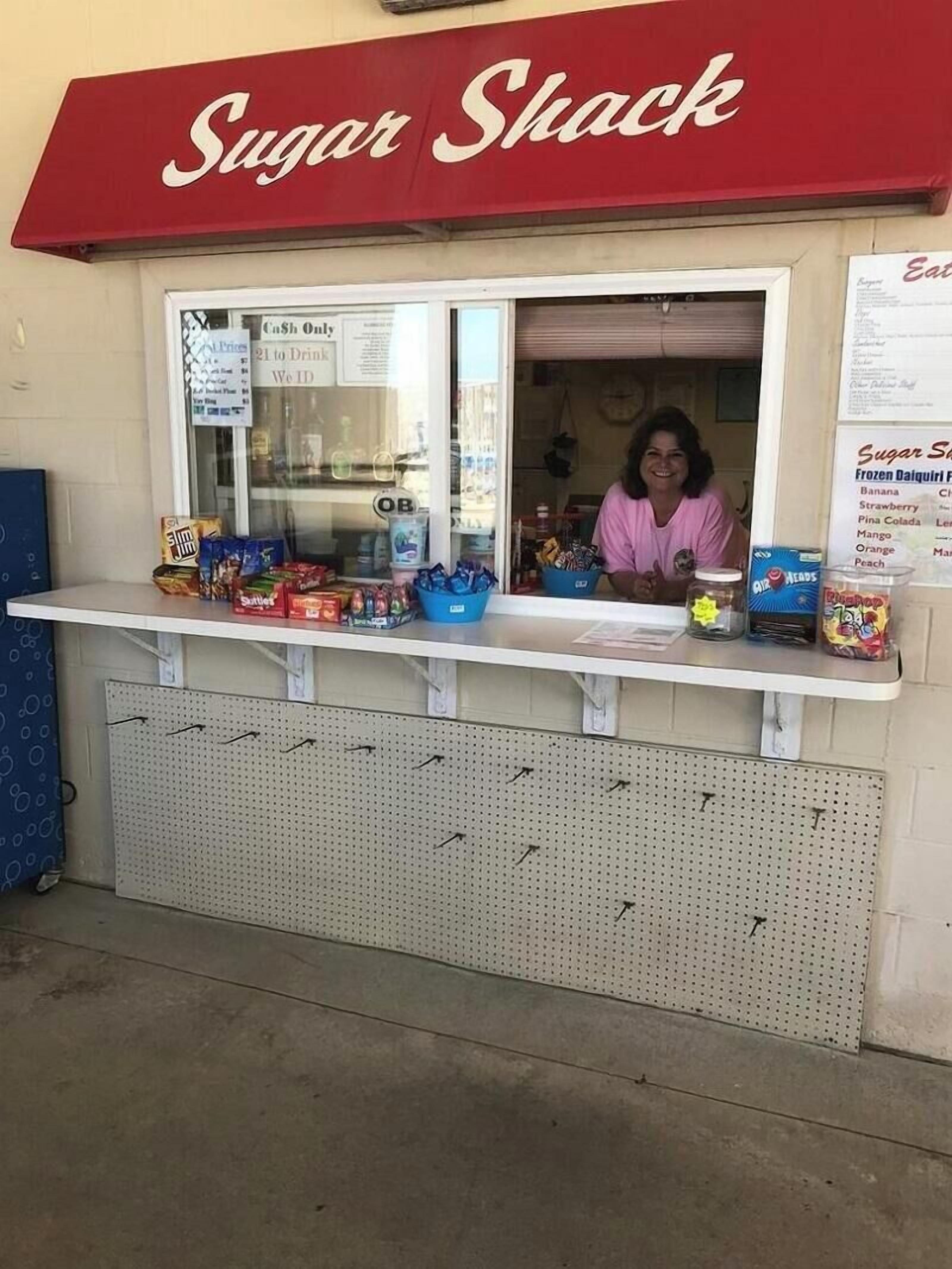A Sugar Shack with a red awning, a cash-only window, and various snacks displayed.