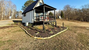 A single-story house with a porch, surrounded by a yard with a wooden fence and a gravel path.