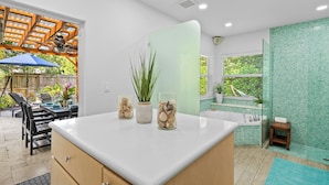 A modern kitchen with a white countertop, wooden cabinets, and a ceiling fan. - New Heated Pool Home in Fort Lauderdale,Charming Tropical Retreat Near Beaches, Shopping & Dining! (Fort Lauderdale)