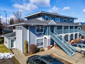 A two-story building with a blue exterior, a front porch, and a staircase leading to the upper level.
