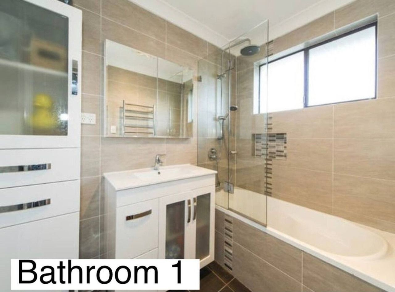 Ein Badezimmer mit einer Duschkabine, einem weißen Waschtisch und einer Badewanne.