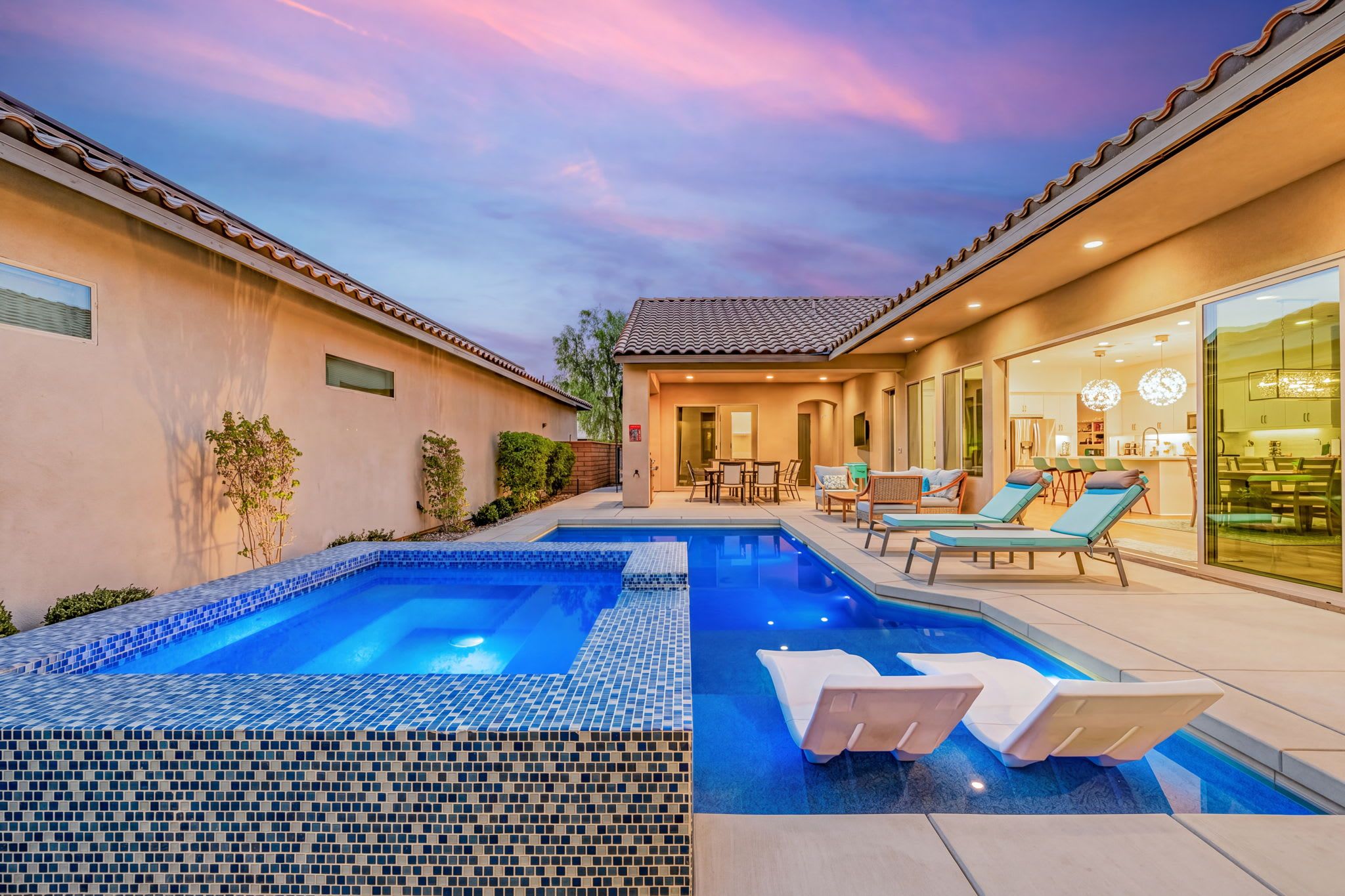 A residential property with a swimming pool, outdoor seating, and a modern kitchen.
