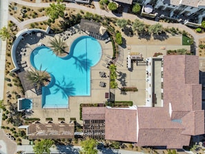 An aerial view of a resort with a large central pool shaped like a heart, surrounded by lounge areas and palm trees. - Palm Oasis: Luxurious home in La Quinta with private heated pool and stunning mountain views. (La Quinta)