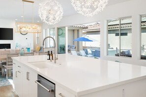 A modern kitchen with a large island, built-in appliances, and pendant lighting.