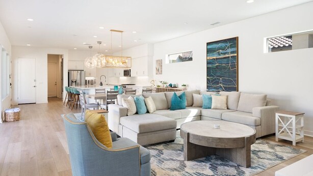 A modern living room with a sofa, coffee table, and a dining area with chairs. - Exclusive Oasis: Pool, Spa & Golf Access (La Quinta)