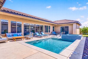 A modern house with a swimming pool, outdoor seating, and large windows.