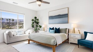 A bedroom with a bed, a nightstand, a chair, a window, and a ceiling fan. - Exclusive Oasis: Pool, Spa & Golf Access (La Quinta)