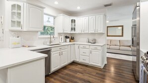 A modern kitchen with white cabinetry, a built-in dishwasher, and a stainless steel refrigerator.