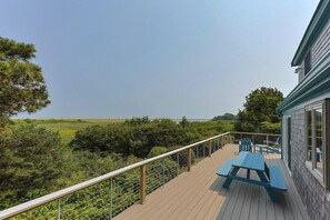 Eine Holzterrasse mit Picknicktischen und Geländer mit Blick auf eine natürliche Landschaft.