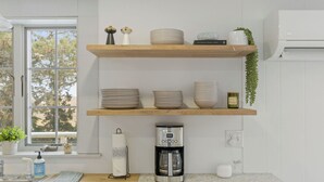 Une cuisine avec deux étagères en bois où sont rangées des assiettes, des bols et une machine à café.