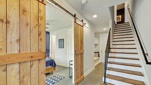 Un interior moderno con una escalera de madera, una puerta corredera y una cama con manta azul.