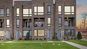 Un edificio de ladrillo de varios pisos con balcones, ventanas amplias y un césped bien cuidado.