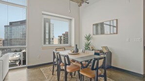 Ein moderner Essbereich mit Tisch, Stühlen und einem großen Fenster mit Jalousien.