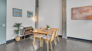 Ein Essbereich mit Holztisch und -stühlen, einer Topfpflanze und Wandbildern.