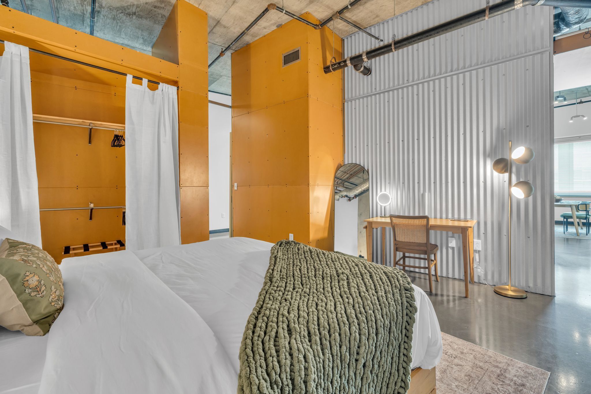 Une chambre d’hôtel moderne avec un grand lit, un bureau en bois et une armoire avec un miroir.