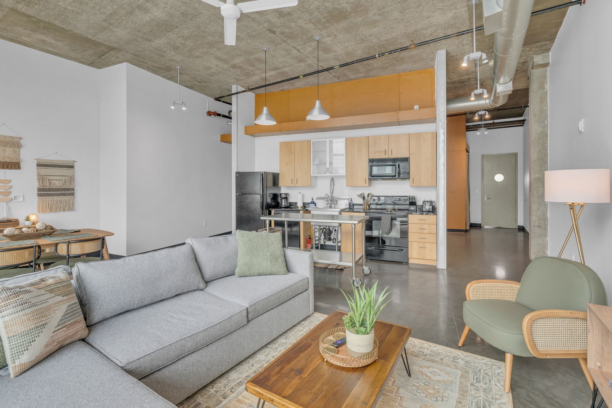 A modern living room with a grey sofa, a wooden coffee table, and a green armchair.