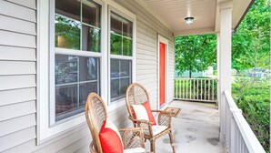 A porch with two wicker chairs and a red door. - Adorable home in fantastic location near restaurants and Duke! (Durham)