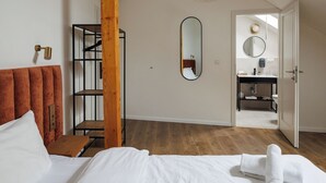 A hotel room with a bed, a wooden wardrobe, a mirror, and a bathroom visible through an open door. - Richter Residence 9 (Brașov)