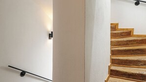 A wooden staircase with a handrail, white walls, and a wooden floor.