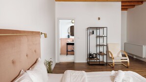 A bedroom with a wooden headboard, a bed with white linens, a wooden chair, a metal shelving unit, and a radiator. - Richter Residence 4 (Brașov)