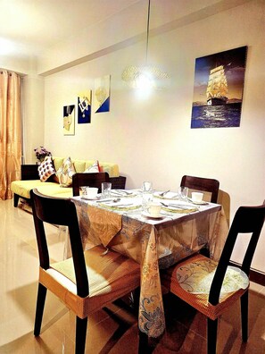 A dining area with a round table set for four, surrounded by wicker chairs with patterned cushions. - Evelyn Azure Escapes Boracay Newcoast  (Boracay Island)