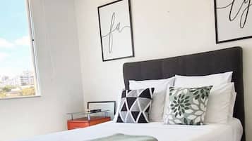 Un dormitorio moderno con una cama grande, una mesita de noche y vistas a la ciudad.