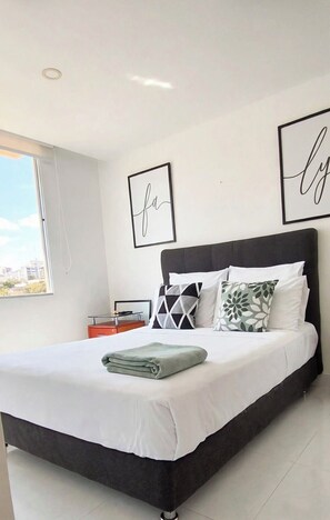A modern bedroom with a large bed, a nightstand, and a view of the city. - Peñalisa Ricaurte Girardot: 2 bedrooms, 2 bathrooms, air conditioning, pool (Ricaurte)