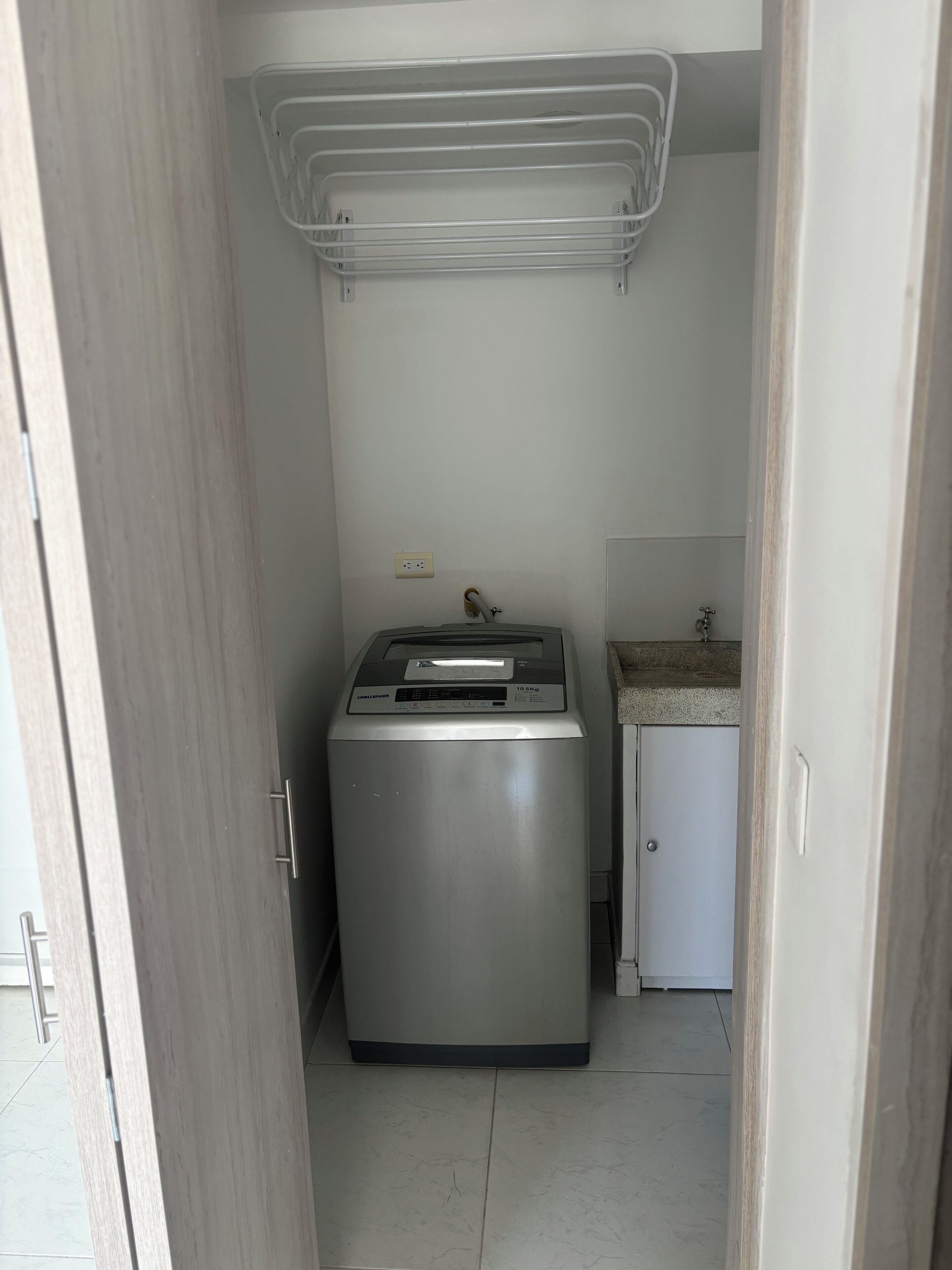 Ein kleiner Hauswirtschaftsraum mit Waschmaschine, einem Schrank und einer Arbeitsplatte.