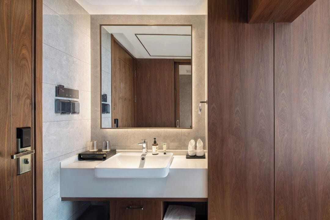 Ein modernes Badezimmer mit großem Spiegel, zwei Waschbecken und Holzschränken.