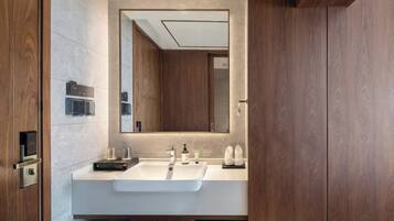 A modern bathroom with a large mirror, two sinks, and wooden cabinetry.