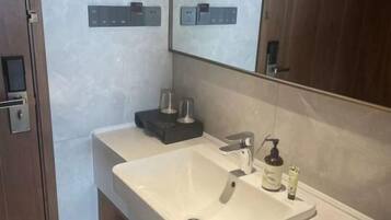A modern bathroom with a large sink, a mirror, and a wooden cabinet.