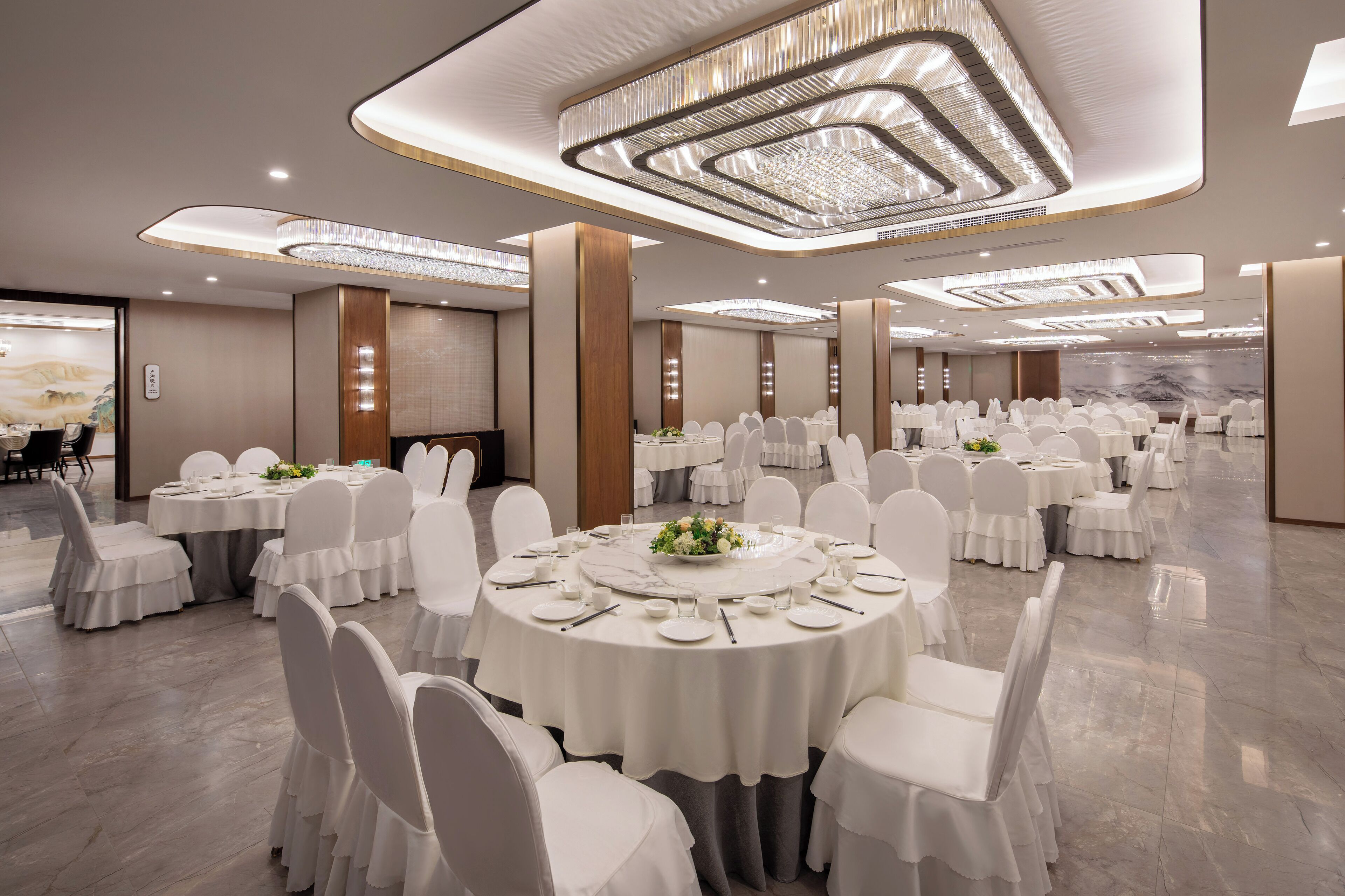Una sala de banquet amb taules rodones, cadires blanques i candelabres.