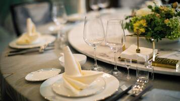 A dining table set with plates, glasses, and cutlery, with a vase of flowers on the right.