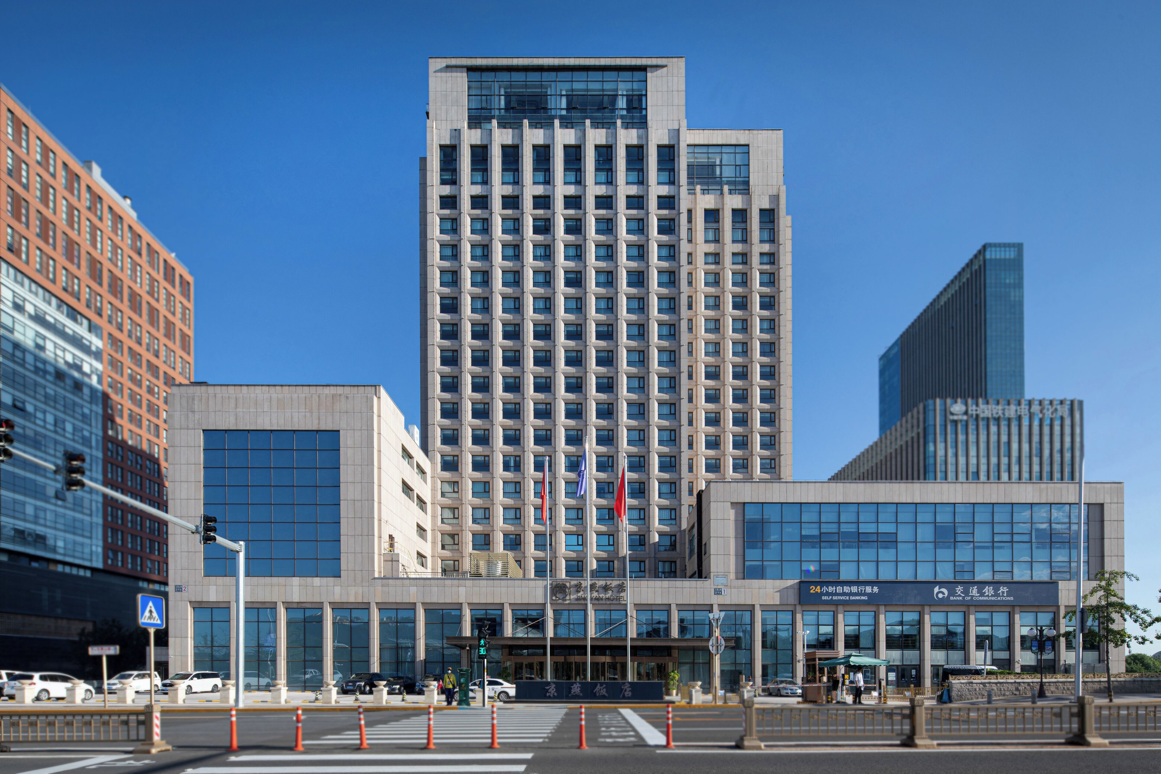 Et moderne hotel med en markant indgang, flere etager og en klar himmel.
