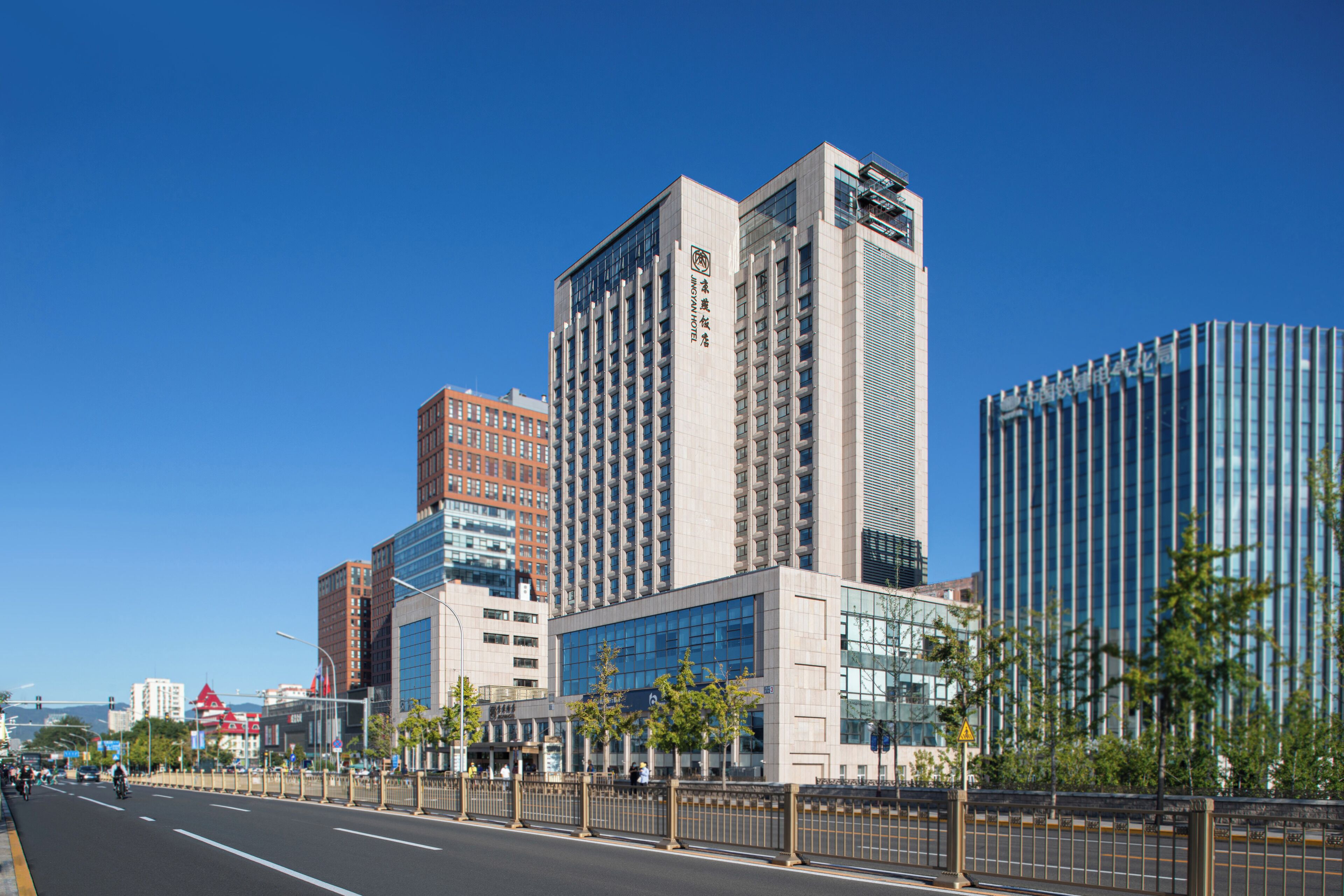 A modern urban street with high-rise buildings, including a prominent hotel with a glass facade and signage.