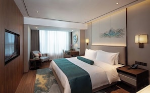A hotel room with a bed, bedside tables, a desk, a chair, a TV, and a painting on the wall. - Beijing Jing Yan Hotel (Beijing)