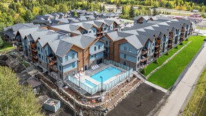 A modern resort with multiple buildings, a swimming pool, and a view of mountains. - All Year Heated Pool & Tub! New! (Bighorn No. 8)