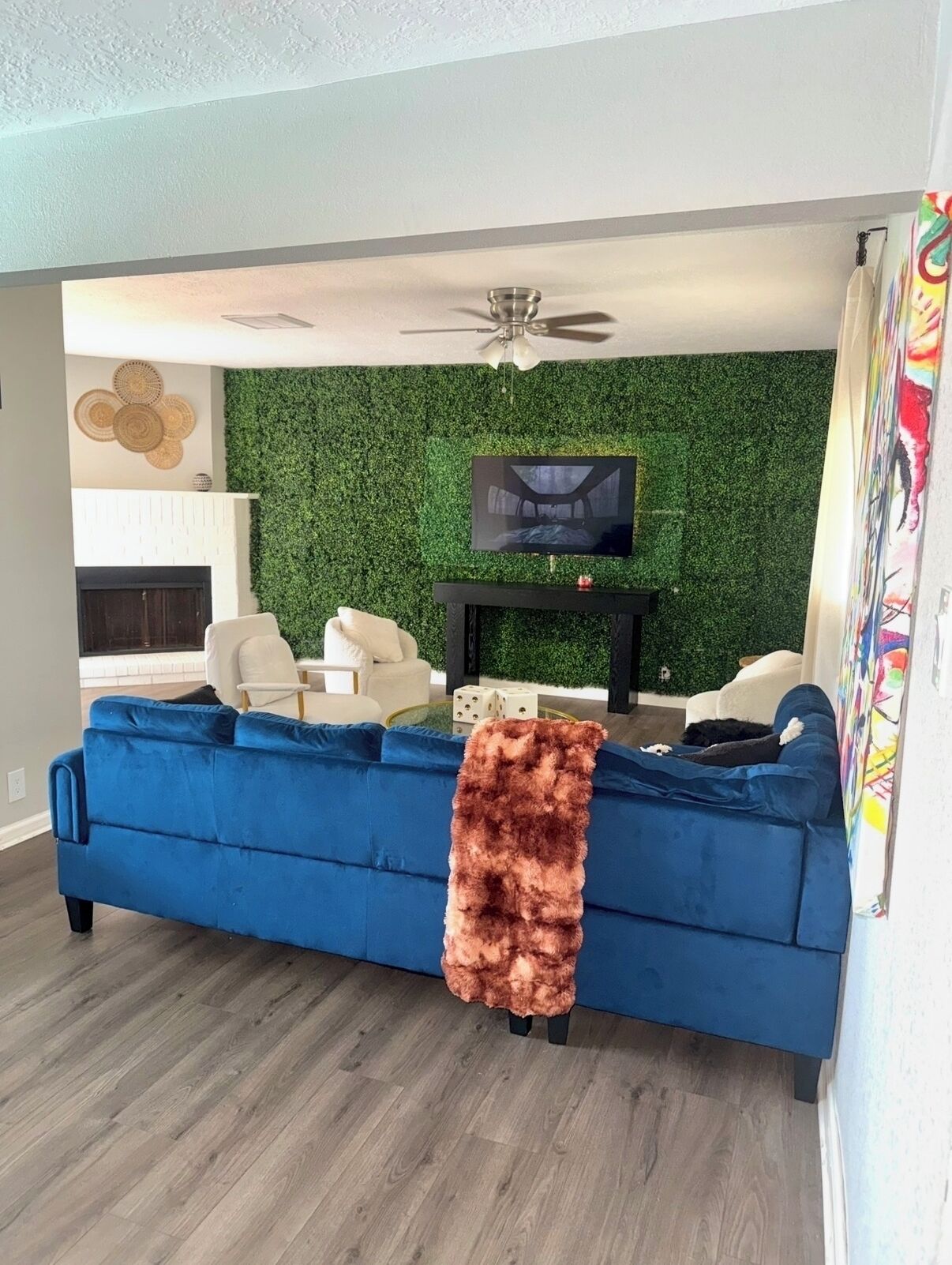 Una sala de estar con un sofá azul, un televisor sobre un mueble negro y una pared verde.