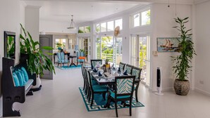 Un comedor amplio con techo alto, ventanas grandes y una mesa central dispuesta para seis comensales.