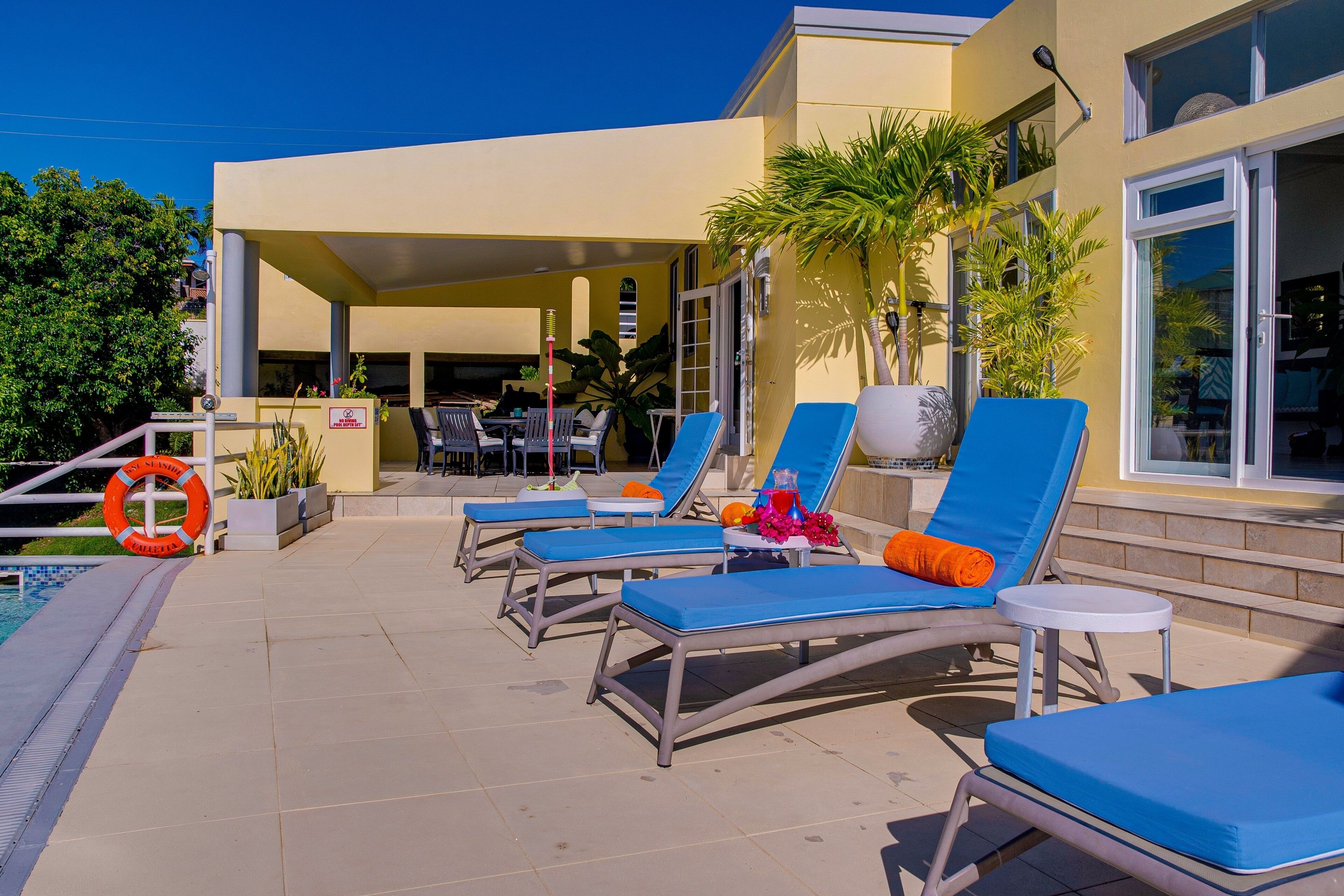A poolside area with lounge chairs, a covered seating area, and a lifebuoy by the pool.