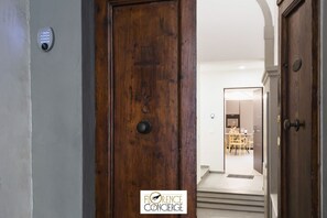 A wooden door with a keypad lock, leading to a room with a dining area and a staircase. - Ground Floor With Patio-Ghibellina 65 apt 1 (Firenze)